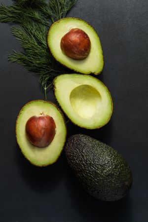 Close up of avocados cut into halves on a dark background