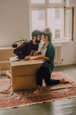 Couple having fun while unpacking boxes at home