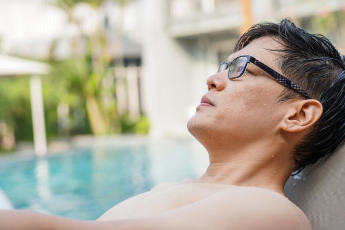 Man in glasses sitting poolside