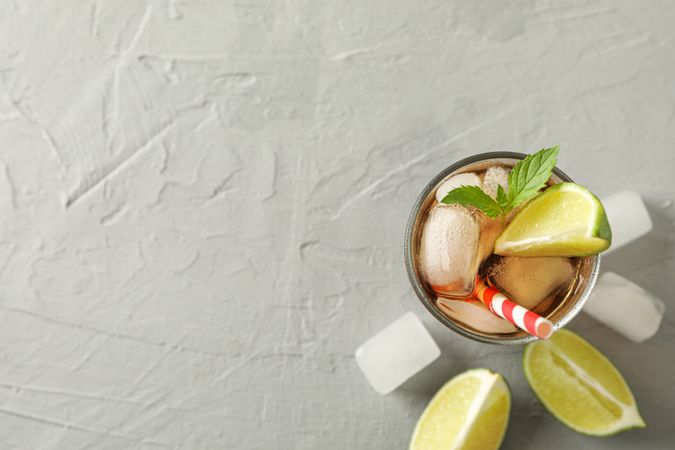Glass with cold cola and citrus on grey cement background, space for text