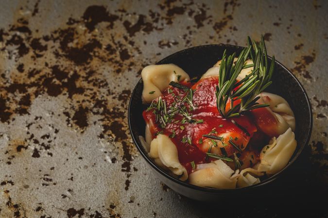 Plate of delicious ravioli with tomato sauce served on table