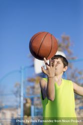 Teenager playing basketball on an outdoors court 5XzjPb