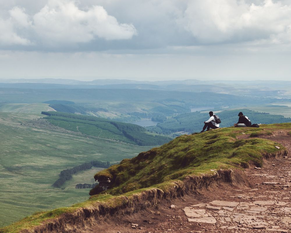 Two people sitting atop a mountain