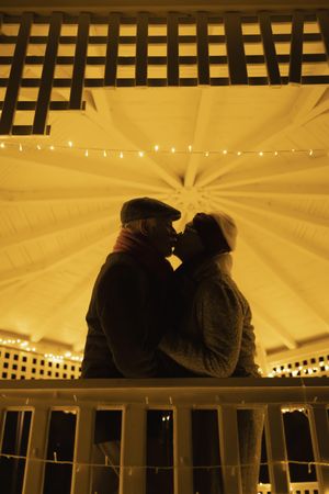Silhouette of older man and woman kissing in a gazebo