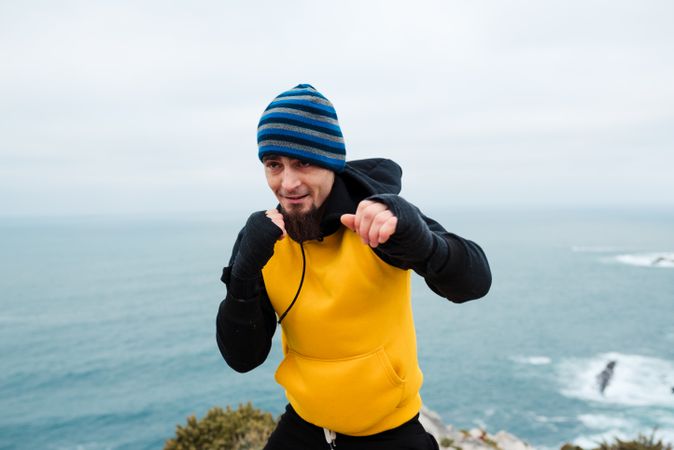 Kickboxer training on cliff near sea