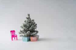 Snowy Christmas tree with presents underneath and pink chair