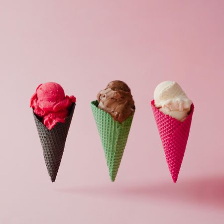 Strawberry, chocolate, and vanilla ice cream in different waffle cones on pink background