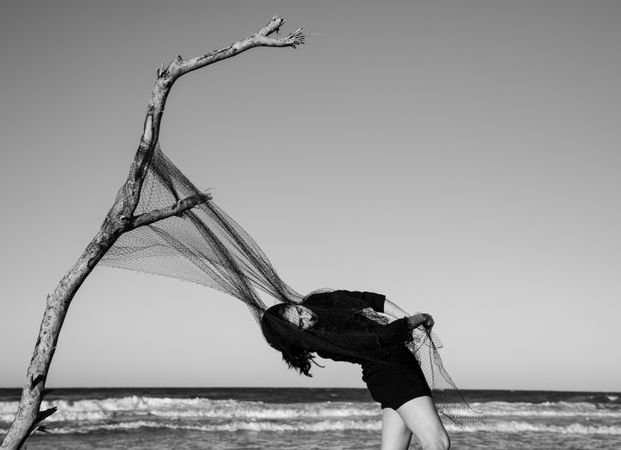 Woman in fishing net fixed on twig near water on shore