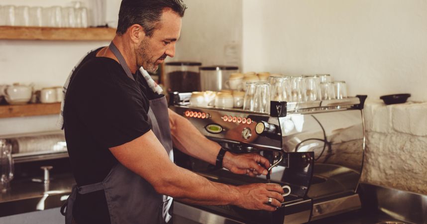Barista using a professional coffee maker to make a cup of espresso