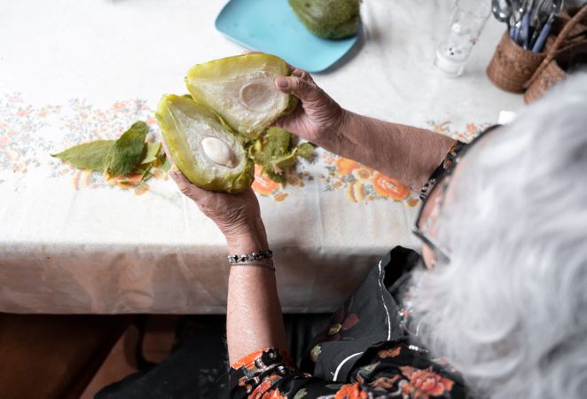 A woman is showing the inside of a fresh cooked chayote after peeling it