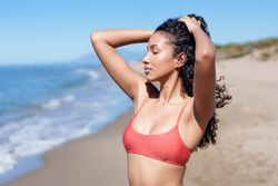 A Young Woman is Joyfully Enjoying a Wonderful Day at the Beach with the Refreshing Ocean Breeze