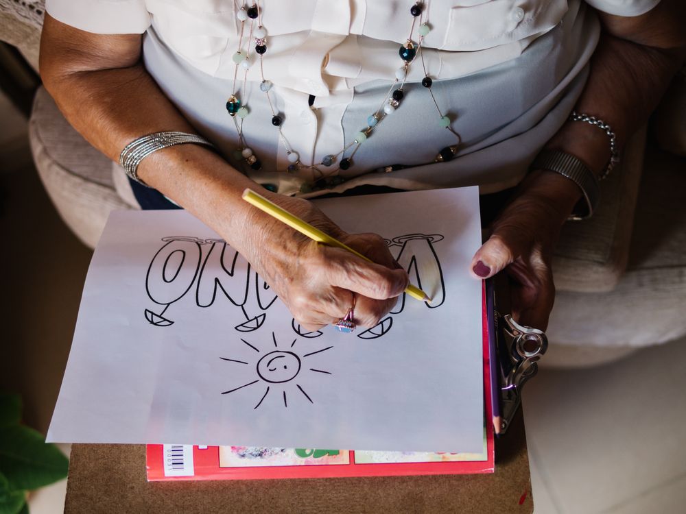 Mature female drawing on paper in apartment