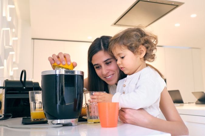 Happy mother and son making orange juice in kitchen
