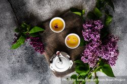 Top view of tray of teapot with filled cups with delicate tea and pink flowers 4d88jn