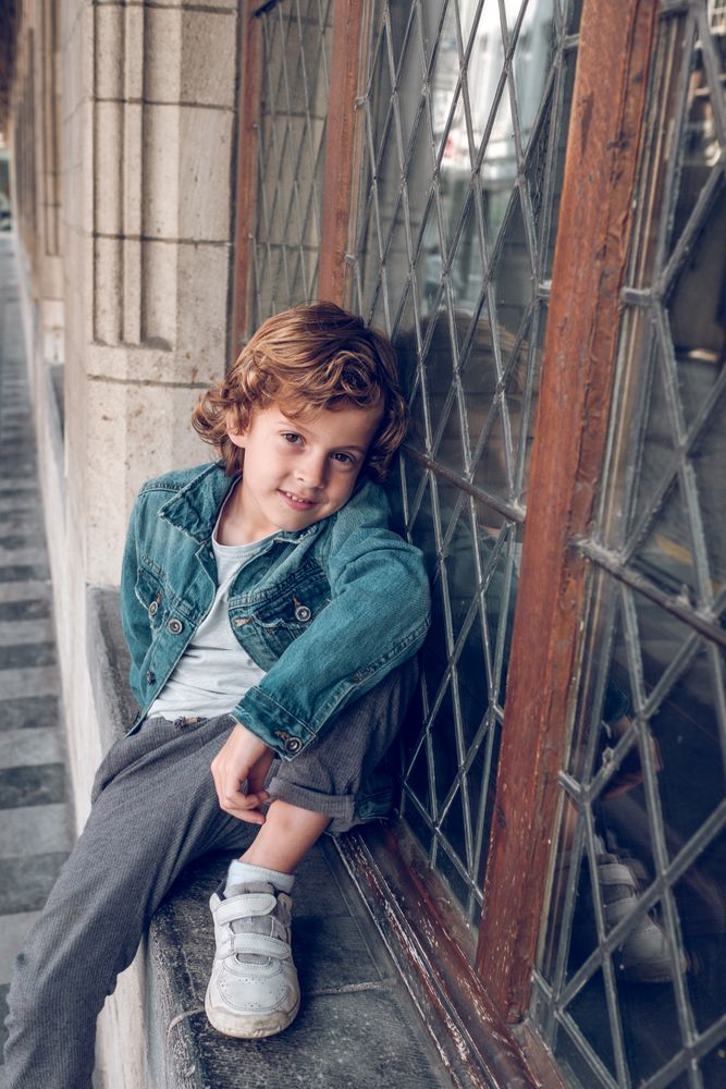 Charming boy sitting near window outside