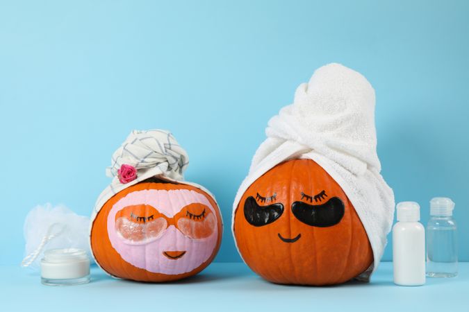 Skincare accessories and pumpkins with eye patches on blue background