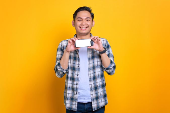 Asian male holding smart phone showing blank screen