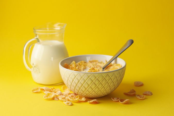 Milk and bowl of muesli on yellow background