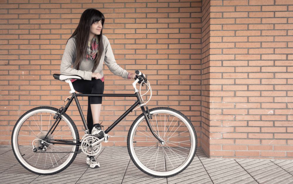 Sportive woman with fixie bike over a brick wall