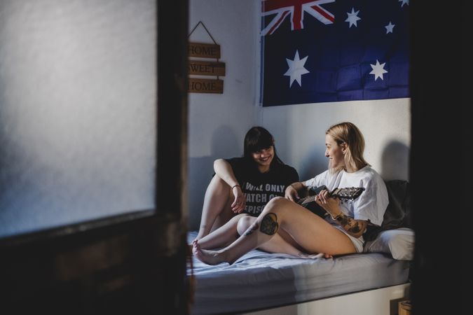 Lesbian couple playing guitar on bed