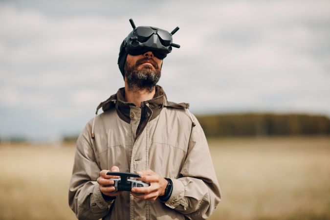 Man wearing electronic goggles holding drone controller