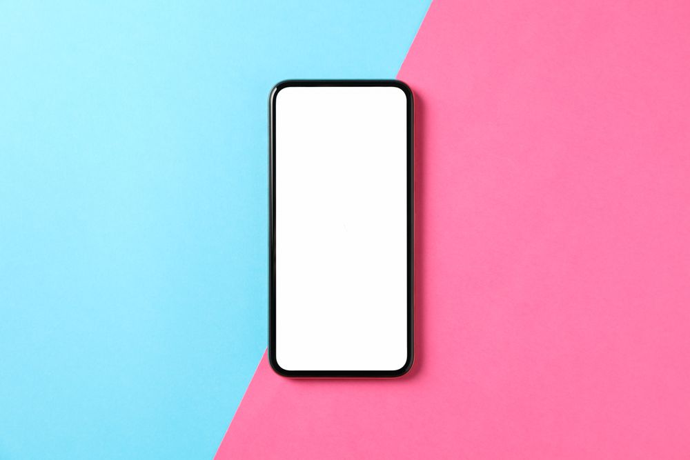 Phone with empty screen on two tone background, top view