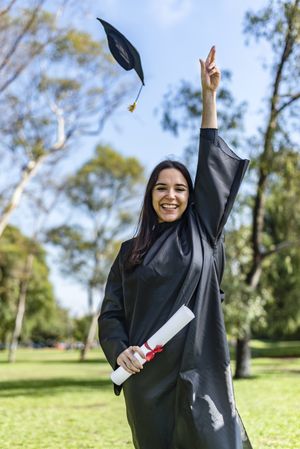 Happy graduated girl in a gown throwing the cap