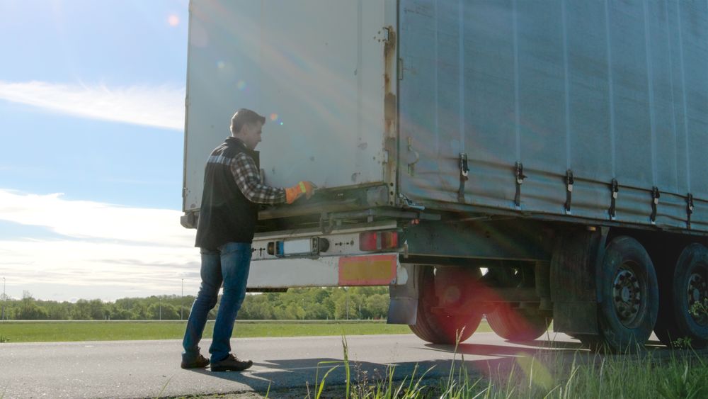 Truck Driver Closes Doors of His Parked  Truck Cargo Trailer.
