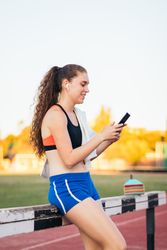 An athletic woman resting with her smartphone after running.