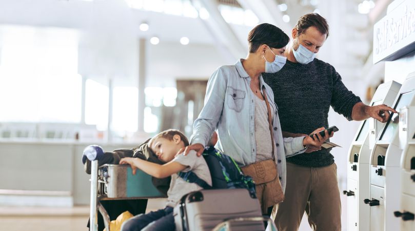 Tourist family doing self check in at airport during pandemic