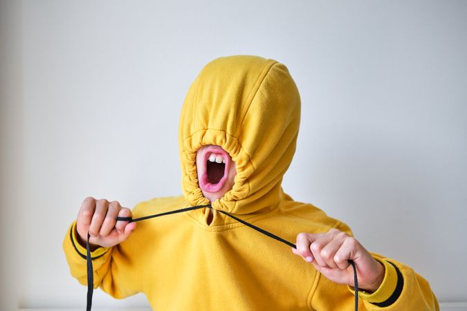 Unrecognizable kid yelling while tightening hood on head in stud