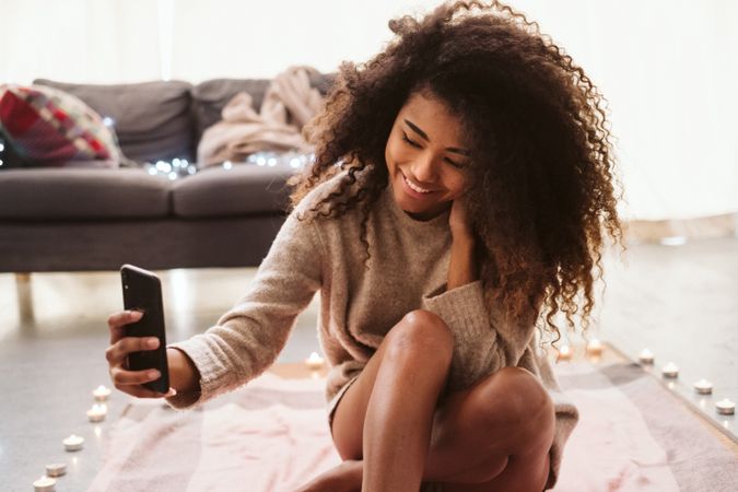 Black woman taking selfie on floor