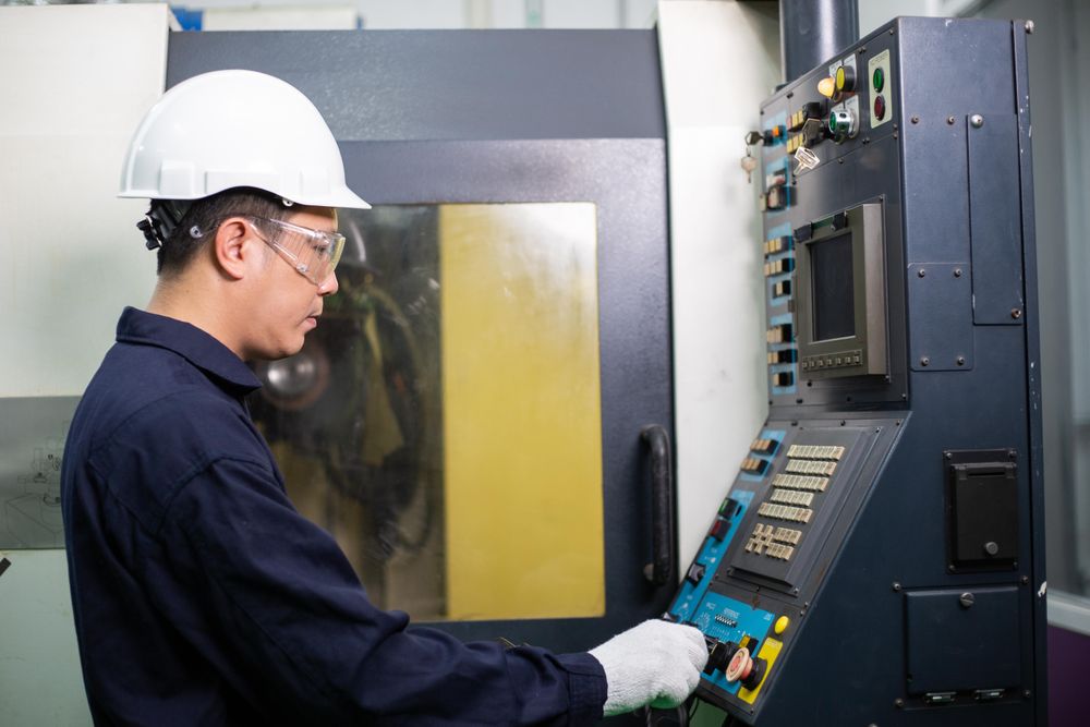 Man operating machinery in construction site in safety helmet and coveralls
