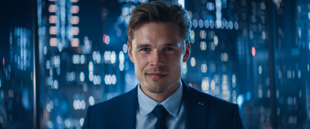 Close Up Portrait of White Businessman in Stylish Suit Posing Next to Window in Big City Office