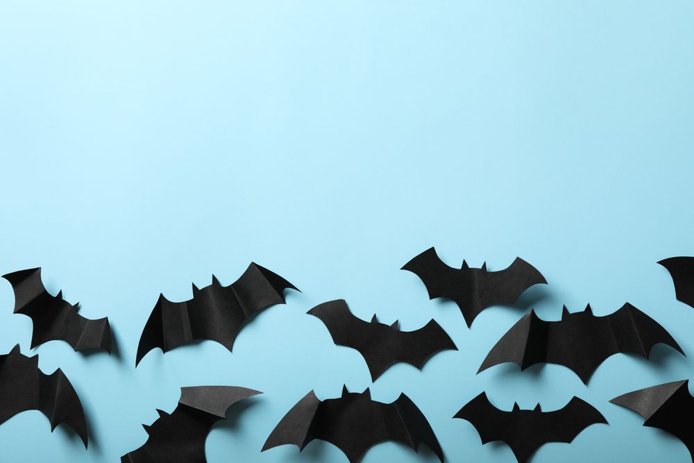 Paper bats on blue background, space for text