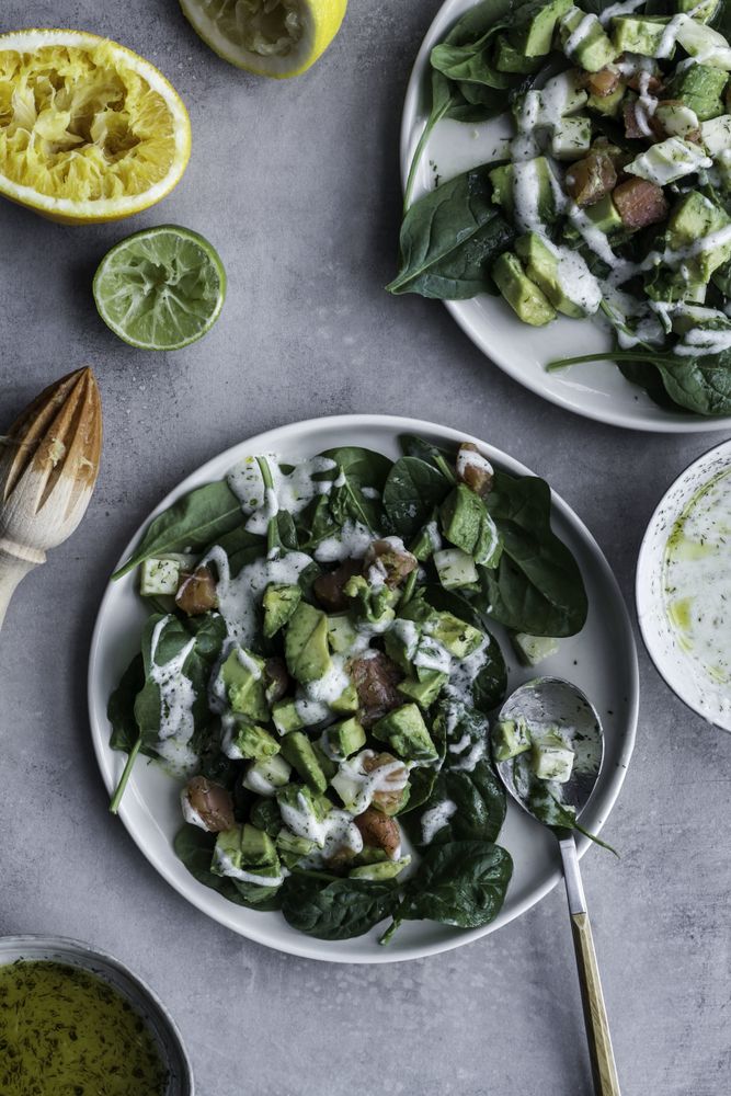 Tasty green salad with salmon on table decorated with citruses