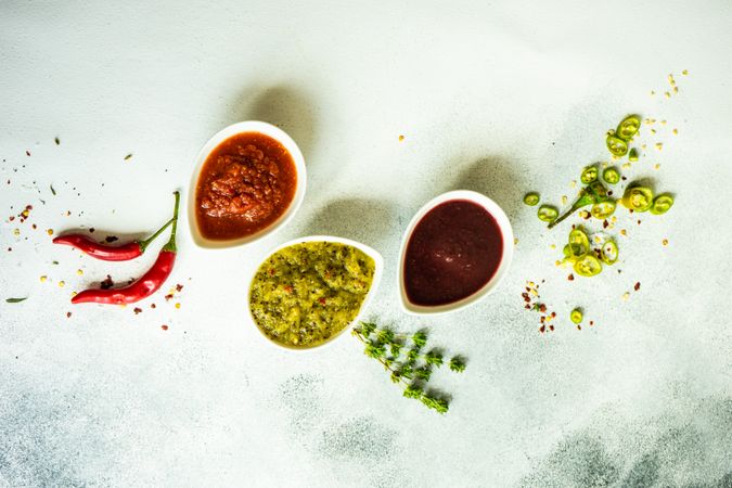 Top view of three colorful spicy traditional Georgian sauces on grey counter