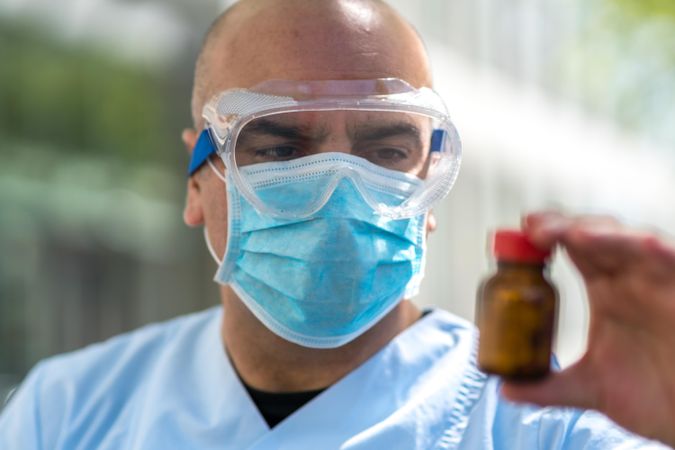 Doctor wearing a medical face mask and googles holding a medicine