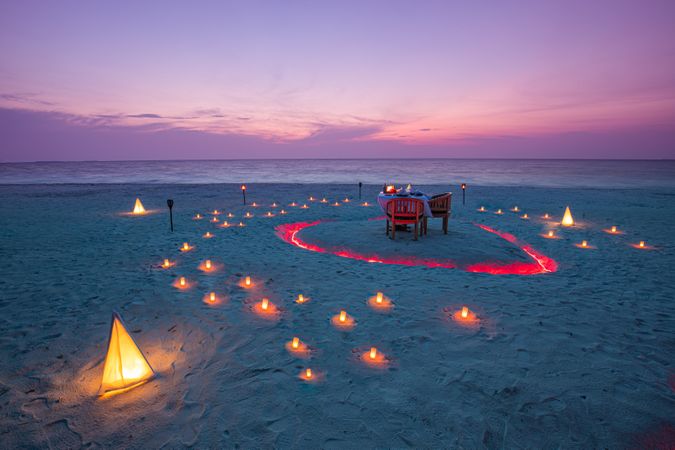 Beautiful dinner setting on a beach with candles at dusk
