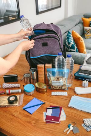 Woman putting a water bottle to prepare emergency backpack