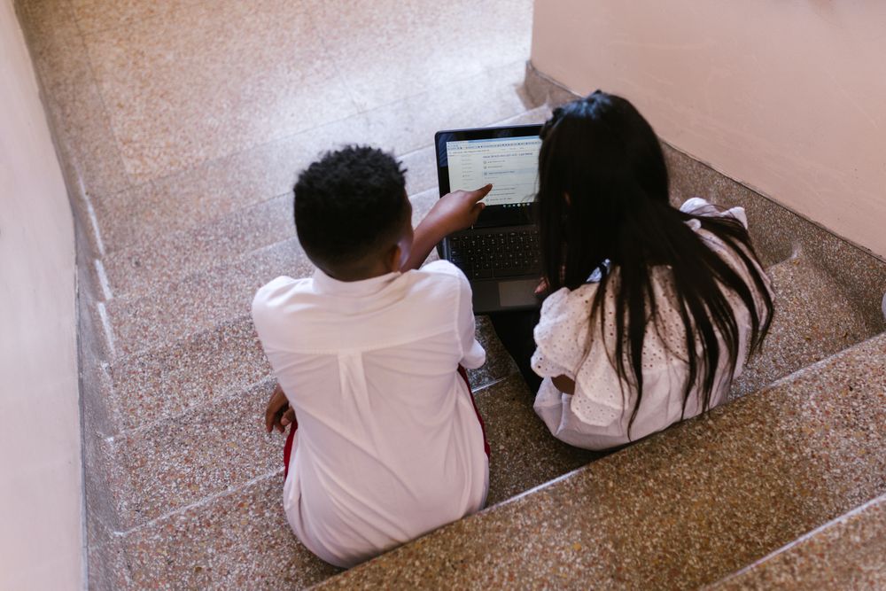 Back view of girl and boy with laptop in school