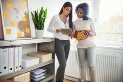 Two women fulfilling orders with a tablet in a bright office