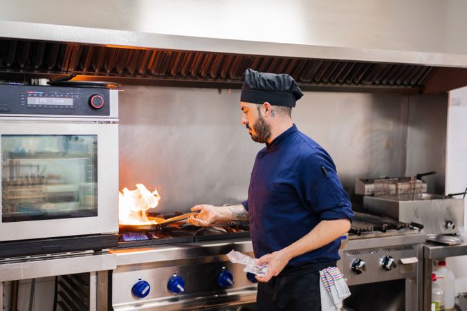 Chef cooking with flame in frying pan