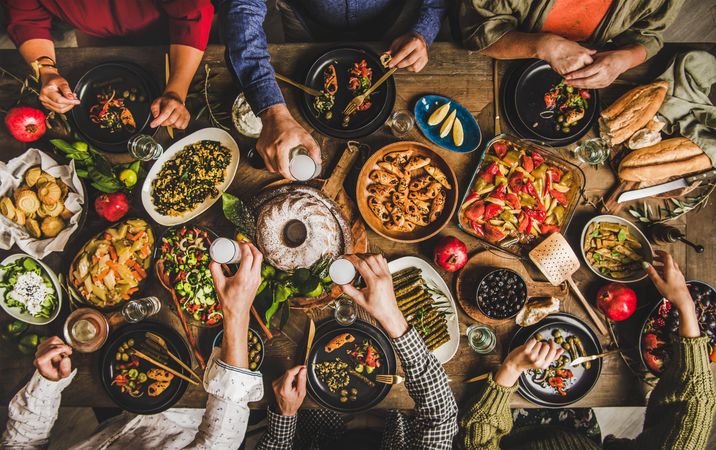 Group of people at wooden table with meze feast and cake toasting with white aperitif