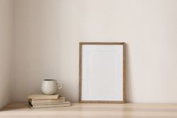 Coffee atop pile of books with blank frame