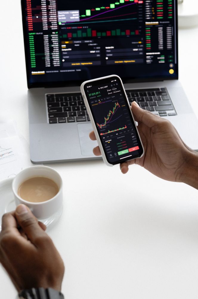Cropped image of person holding a cup of coffee while checking the stock market