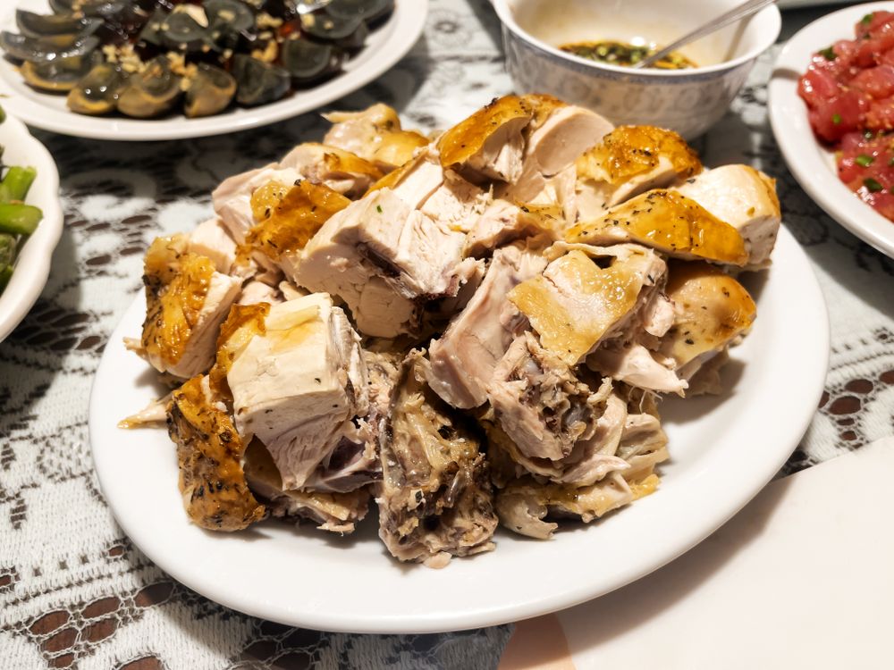 Close up view of fried chicken pieces on plate surrounded by other food dishes on table