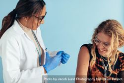 Smiling young woman getting vaccine from a female doctor 5zYEN0