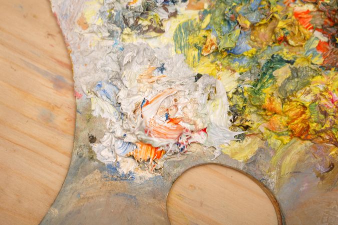 Painter palette with light shades of paint being mixed