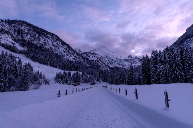 Snow-covered road at sunset, winter scenery in the Bavarian Alps, Germany
